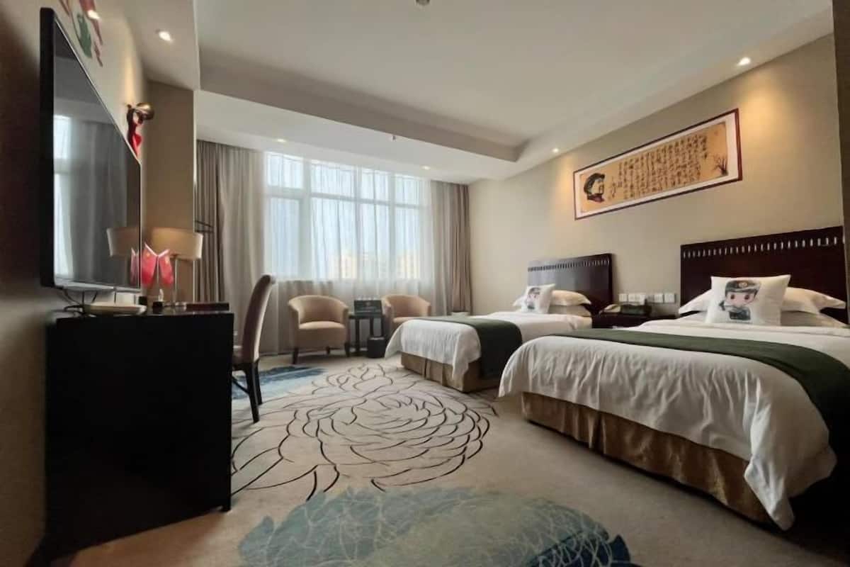 Habitación de hotel con dos camas, un televisor de pantalla plana, un escritorio y un ventanal grande.