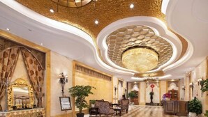 Um hall luxuoso com piso estampado, decorações elaboradas nas paredes e um grande candelabro.