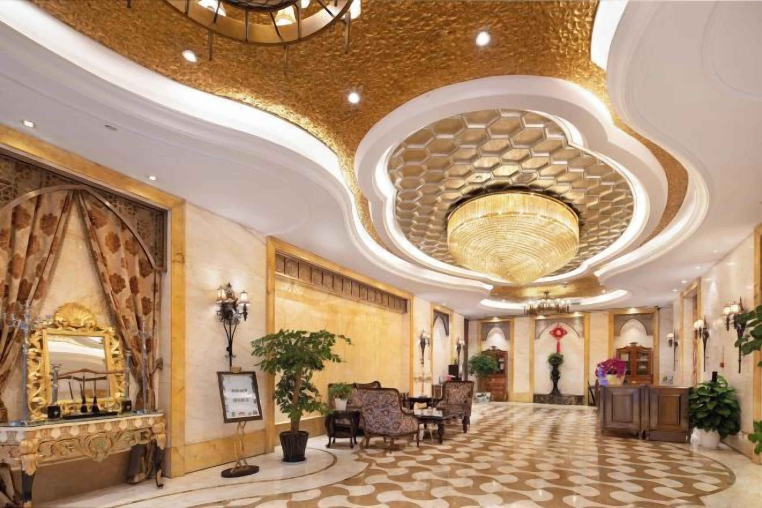 A grand lobby with a patterned floor, a large chandelier, and ornate decor.