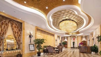 A grand lobby with a patterned floor, a large chandelier, and ornate decor.