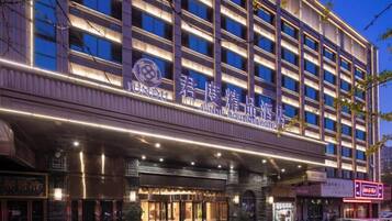 A multi-story hotel with illuminated signage, a covered entrance, and a visible storefront.