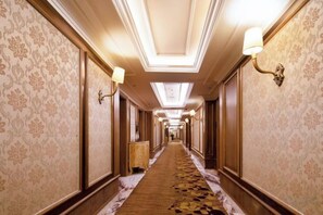 A hotel corridor with patterned wallpaper, wall sconces, and a carpeted floor. - Jundu Boutique Hotel (Jinhua Stadium) (Jinhua)