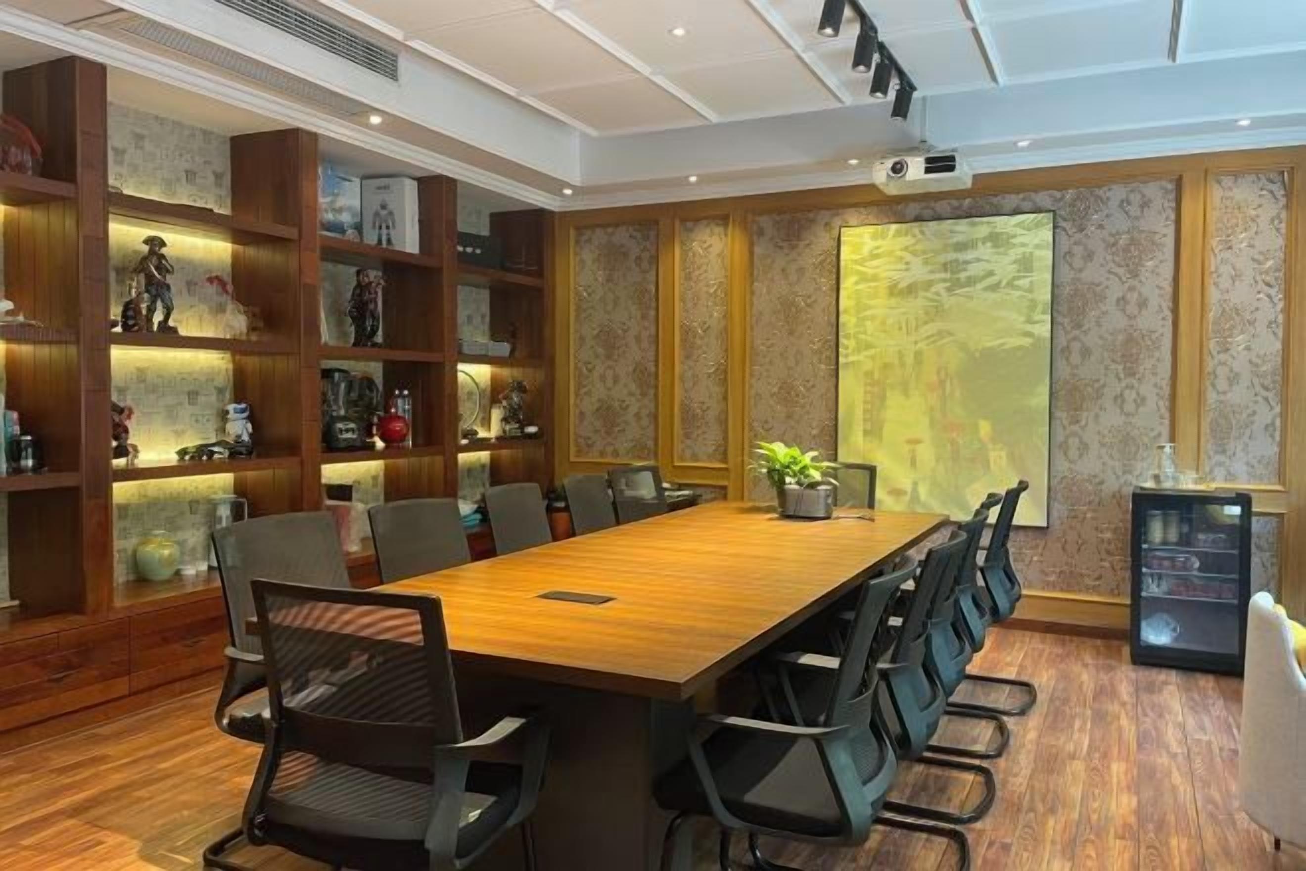 Un salón de conferencias con una mesa larga, sillas, un proyector y una estantería.