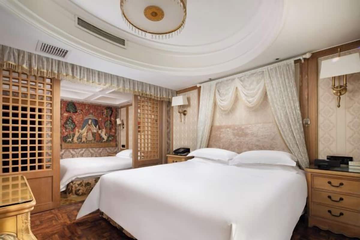 Une chambre d’hôtel avec un grand lit, une tête de lit en bois, une table de chevet, une lampe et un panneau décoratif mural.