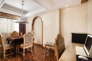 A dining area with a wooden table and chairs, a computer desk with a monitor and keyboard, and a patterned wall. - Jundu Boutique Hotel (Jinhua Stadium) (Jinhua)