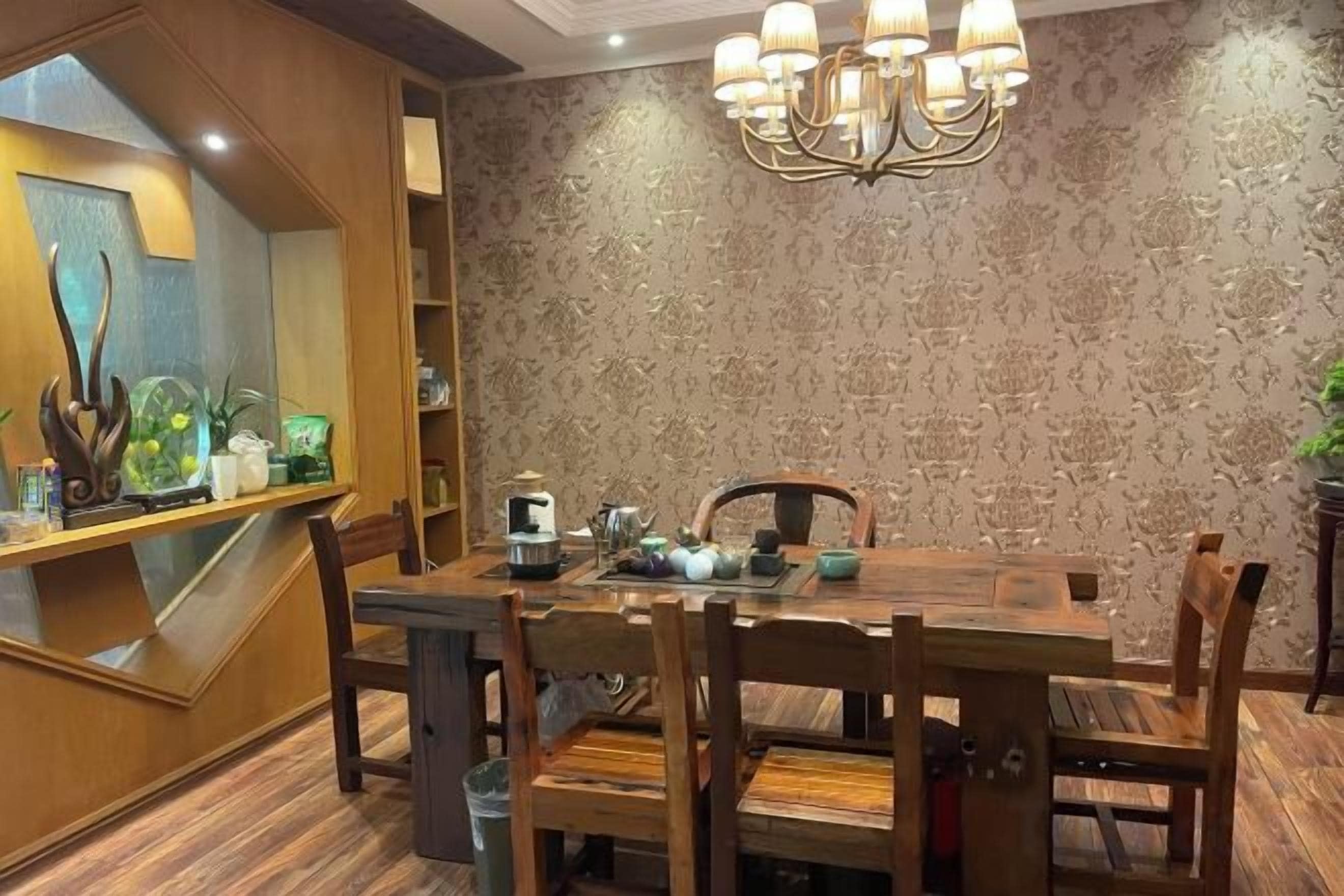 A dining area with a wooden table and chairs, a chandelier, and a patterned wall.
