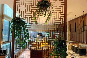 A room with a geometric patterned wall, a dining area with a table and chairs, and a hanging plant. - Jundu Boutique Hotel (Jinhua Stadium) (Jinhua)