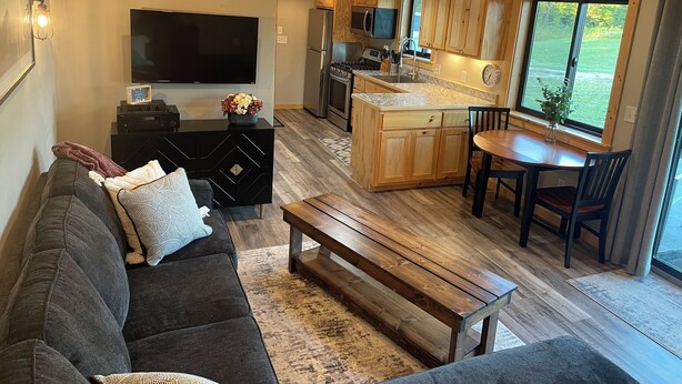 Una cocina moderna con armarios de madera, una isla central y una zona de comedor con mesa y sillas.