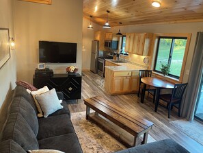 A modern kitchen with wooden cabinets, a central island, and a dining area with a table and chairs. - "Outdoors Oasis" Cozy cabin north of Bemidji.    (Bemidji)
