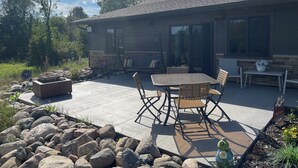 Un patio con un hogar a leña de piedra, mobiliario exterior y una pared de piedra.