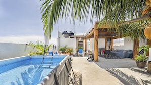 Un espace piscine sur le toit offrant une vue dégagée sur la mer, un coin salon couvert et des plantes en pot.