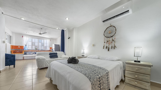 Une chambre à coucher moderne avec un grand lit, des tables de chevet et une vue sur la cuisine.