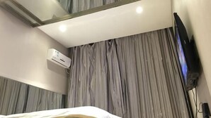 A hotel room with a bed, a television, an air conditioning unit, and a curtain wall. - Friendship City New Town Hotel (Youyi)
