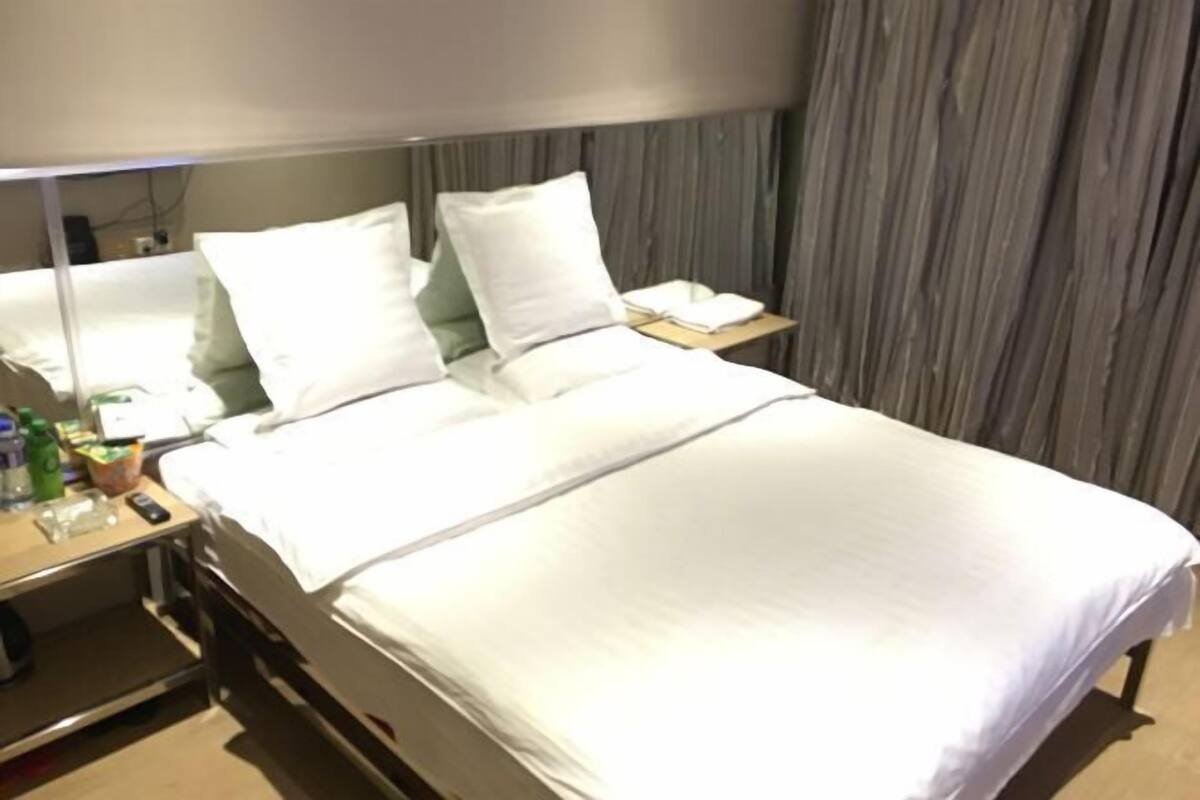 Hotellihuone, jossa on sänky, yöpöytä ja peili.