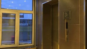 A hotel room with a large window, a door with a number plate, and a radiator. - Friendship City New Town Hotel (Youyi)
