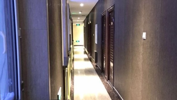 A hotel corridor with doors on both sides, a tiled floor, and a light source at the end. - Friendship City New Town Hotel (Youyi)