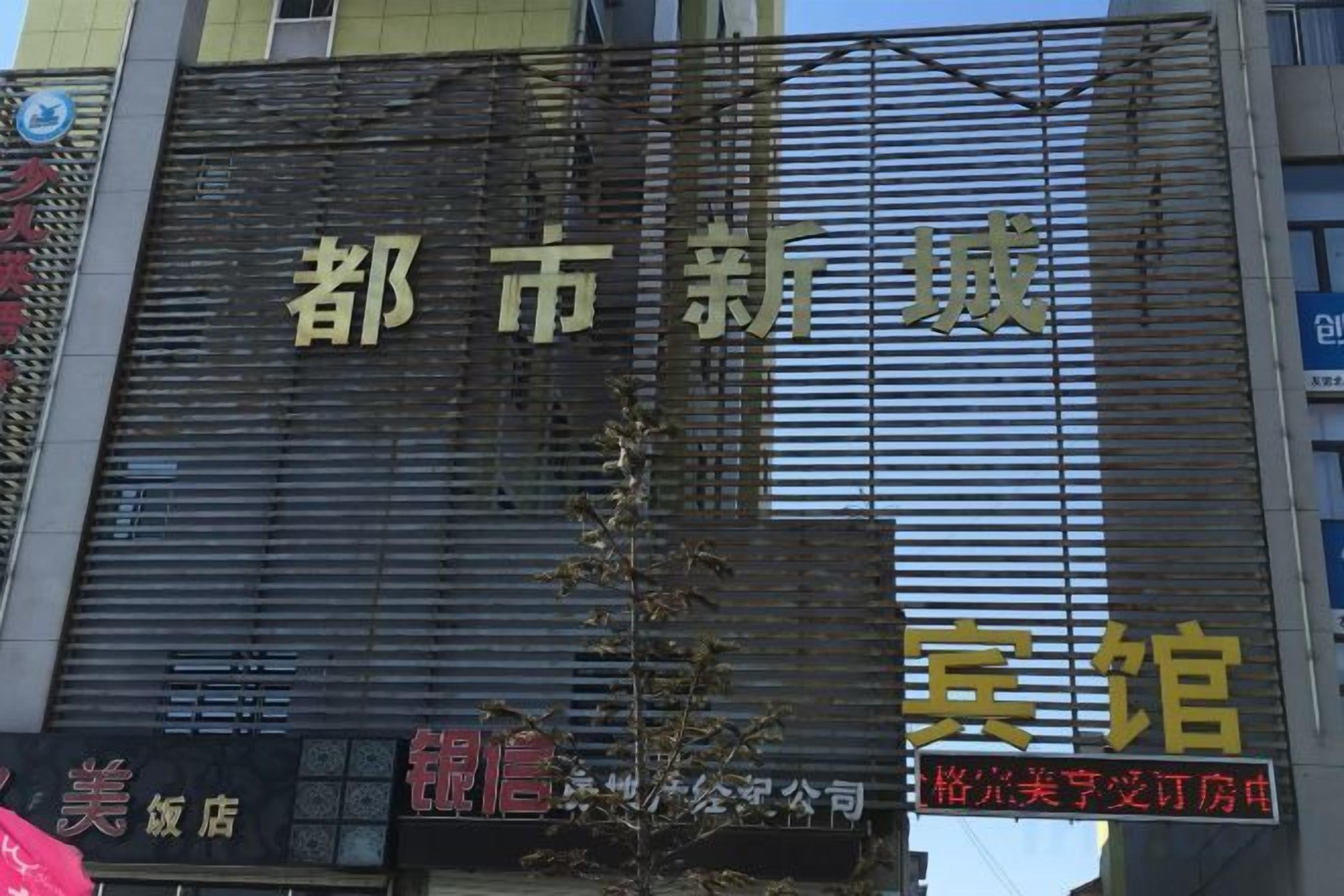 A hotel sign with the name '都市新城' and a smaller sign below stating '美酒店'.