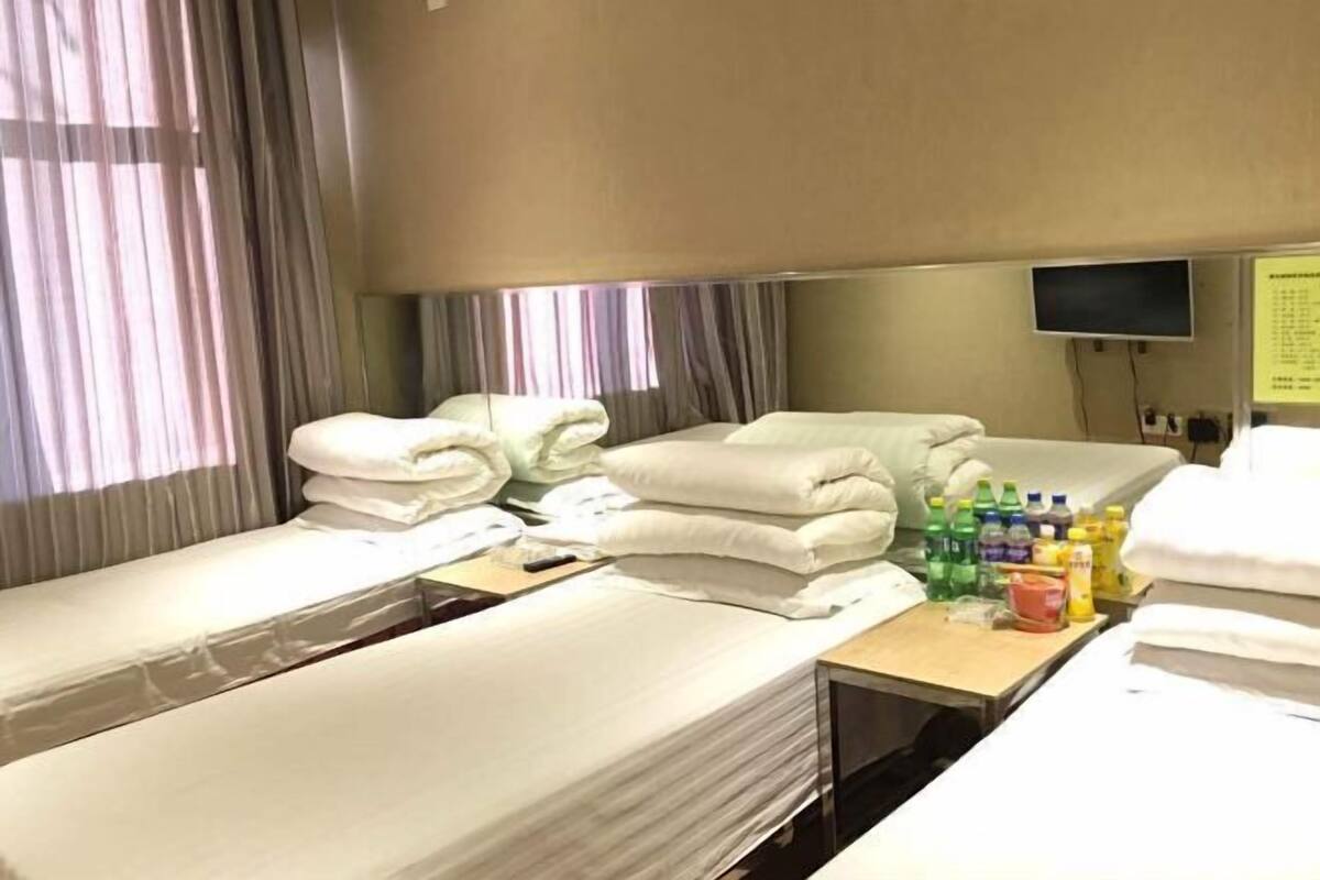 Hotellihuone, jossa on kaksi erillistä sänkyä, työpöytä, jossa on hygieniatarvikkeita, televisio ja ikkuna, jossa on verhot.