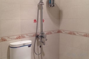 Un área de ducha con cabezal de ducha de mano, grifo empotrado en la pared y un inodoro.