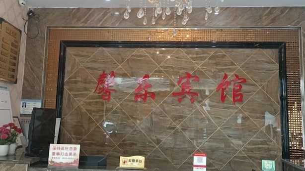 A reception area with a marble wall, a chandelier, and a sign with Chinese characters. - Citadel Luoping (Luoping)