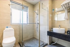 A bathroom with a glass-enclosed shower, a white toilet, a sink with a black countertop, and a mirror above the sink. - Weistin Hotel (Taishan)