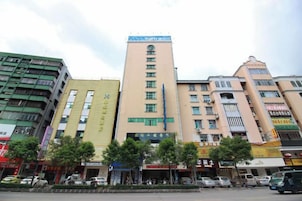 Un edificio de varios pisos con una torre central, rodeado de otros edificios.