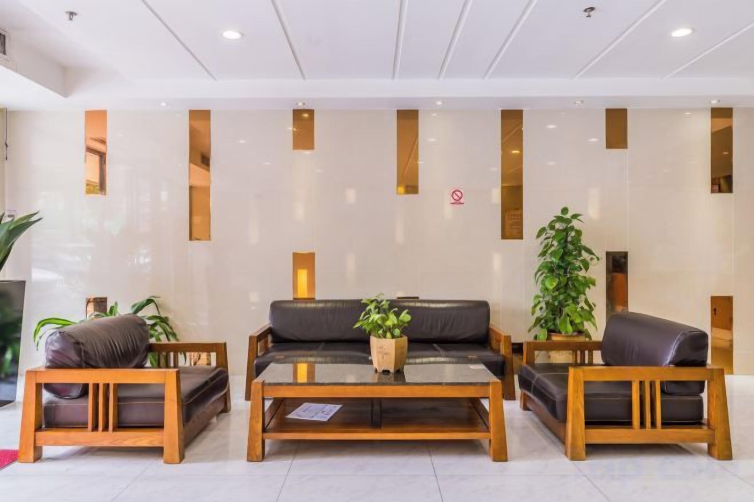 Un área de recepción con un sofá, dos sillas de madera, una mesa de centro y una planta en maceta.