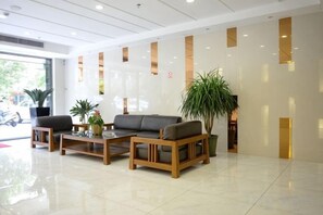 Un área de recepción con un sofá, sillas, una mesa de centro y una planta en maceta.