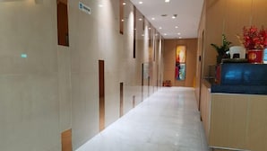 Ένα σύγχρονο λόμπι ξενοδοχείου με έναν μακρύ διάδρομο, έναν πάγκο υποδοχής και έναν μεγάλο π ίνακα στον τοίχο.