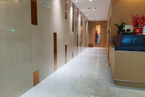 A hotel corridor with a reception desk, a plant, and a sign on the wall. - Weistin Hotel (Taishan)