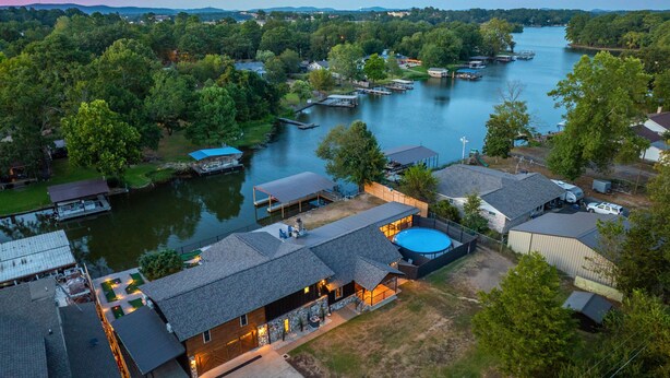 A lakeside property with multiple docked boats, a swimming pool, and a variety of buildings with different roof styles.