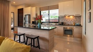 A modern kitchen with a central island, stainless steel appliances, and a view of the outdoors. - Andaman 3Br Pool Villa （IV2V7） (Phuket)
