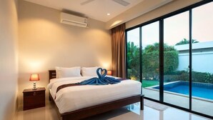 A bedroom with a bed, nightstand, and a view of a swimming pool. - Andaman 3Br Pool Villa （IV2V7） (Phuket)