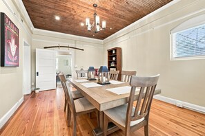 A dining area with a wooden table and chairs, a chandelier, and a bookshelf. - Historic Carriage House in Downtown 
119 S. Marshall St. Winston-Salem, NC 27101 (Winston-Salem)