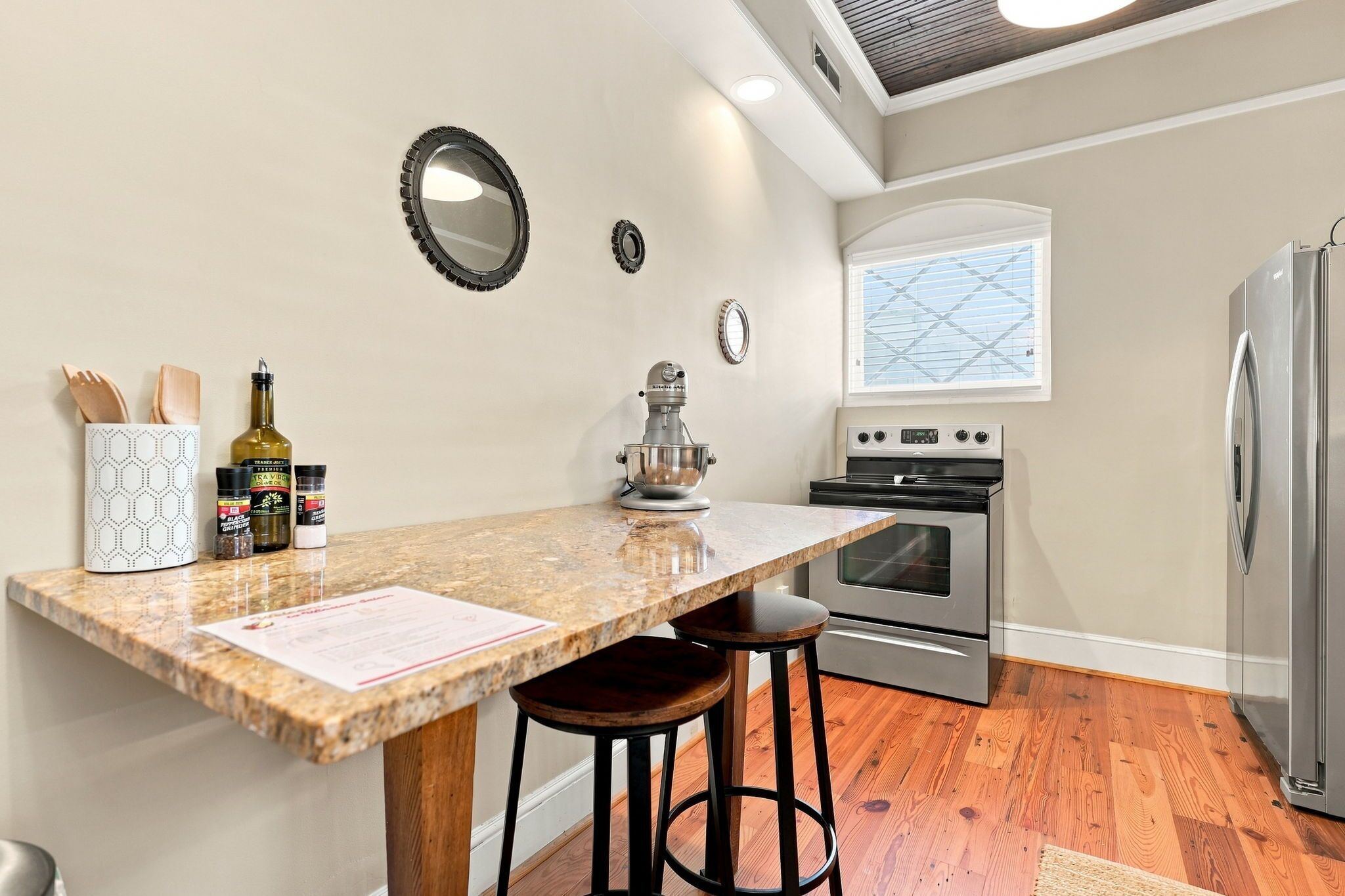 A kitchen with a granite countertop, a mixer, an oven, and a refrigerator.