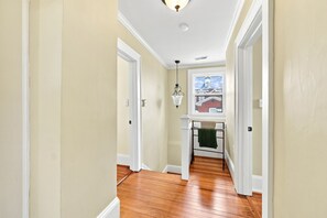 A hallway with wooden flooring, white walls, and a window with a view of a building outside. - Historic Carriage House in Downtown 
119 S. Marshall St. Winston-Salem, NC 27101 (Winston-Salem)