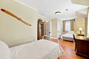 A hotel room with two beds, a wooden cabinet, a desk with a lamp, and a ceiling light fixture. - Historic Carriage House in Downtown 
119 S. Marshall St. Winston-Salem, NC 27101 (Winston-Salem)
