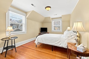 A bedroom with a bed, a TV, and a bedside table with a lamp and tissues.