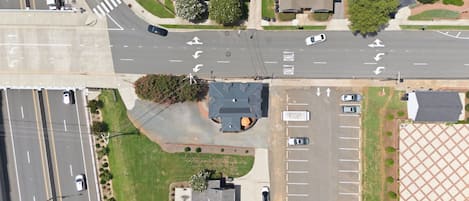 An aerial view of a multi-lane road intersecting with a roundabout, surrounded by residential buildings and a parking lot.