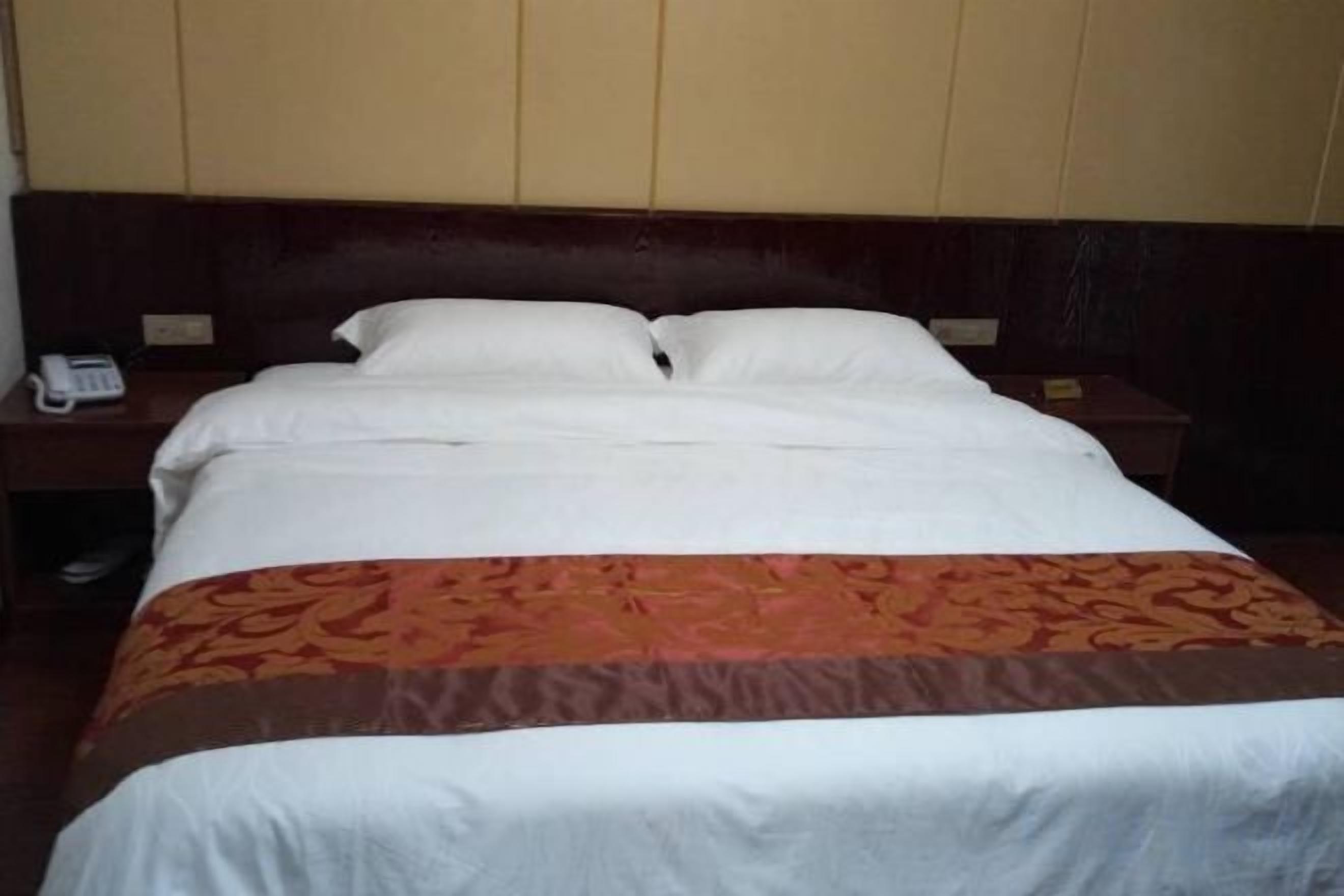 A hotel room with a bed, a bedside table, and a telephone.