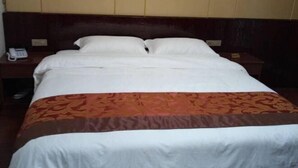 Hotellihuone, jossa on sänky, kaksi yöpöytää ja toisella yöpöydällä puhelin.
