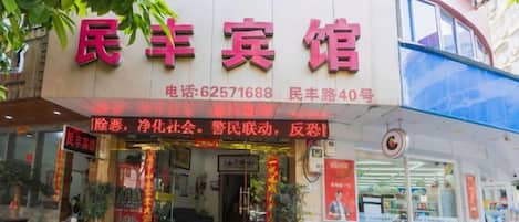 Une devanture de magasin avec une enseigne en caractères chinois, un numéro de téléphone et une adresse.