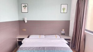 A hotel room with a bed, bedside tables, a lamp, and framed pictures on the wall. - Minfeng Hotel (Yueqing)