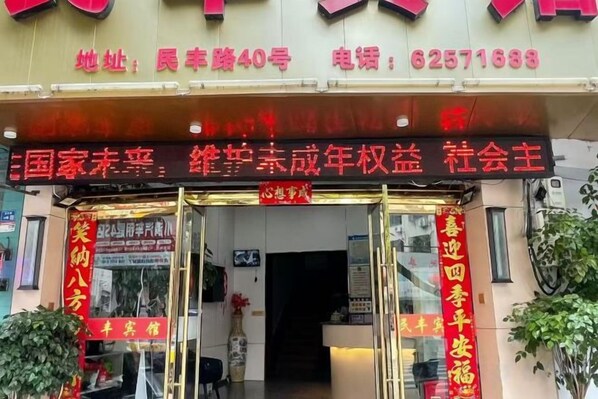 A storefront with a glass entrance, signage in Chinese, and a telephone number. - Minfeng Hotel (Yueqing)