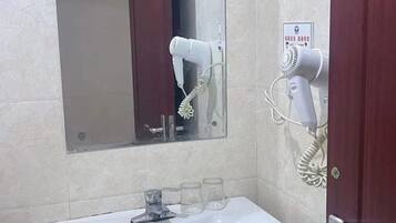A bathroom with a sink, mirror, and two hair dryers mounted on the wall.