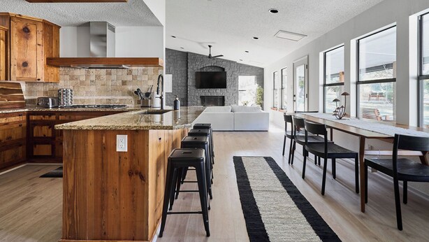 Una cocina moderna con una isla grande, armarios de madera y un protector contra salpicaduras de piedra.