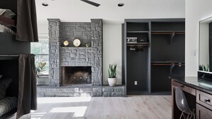 Una sala de estar moderna con chimenea de piedra, ventilador de techo y estantería empotrada.