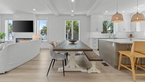 A modern kitchen with a large island, white cabinetry, and pendant lighting.