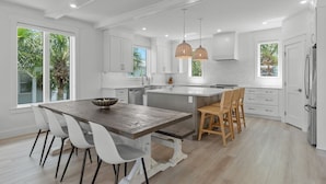 A modern kitchen with white cabinetry, a central island, and pendant lighting.