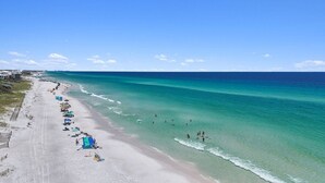 A beach with clear turquoise water, a sandy shore, and several umbrellas.